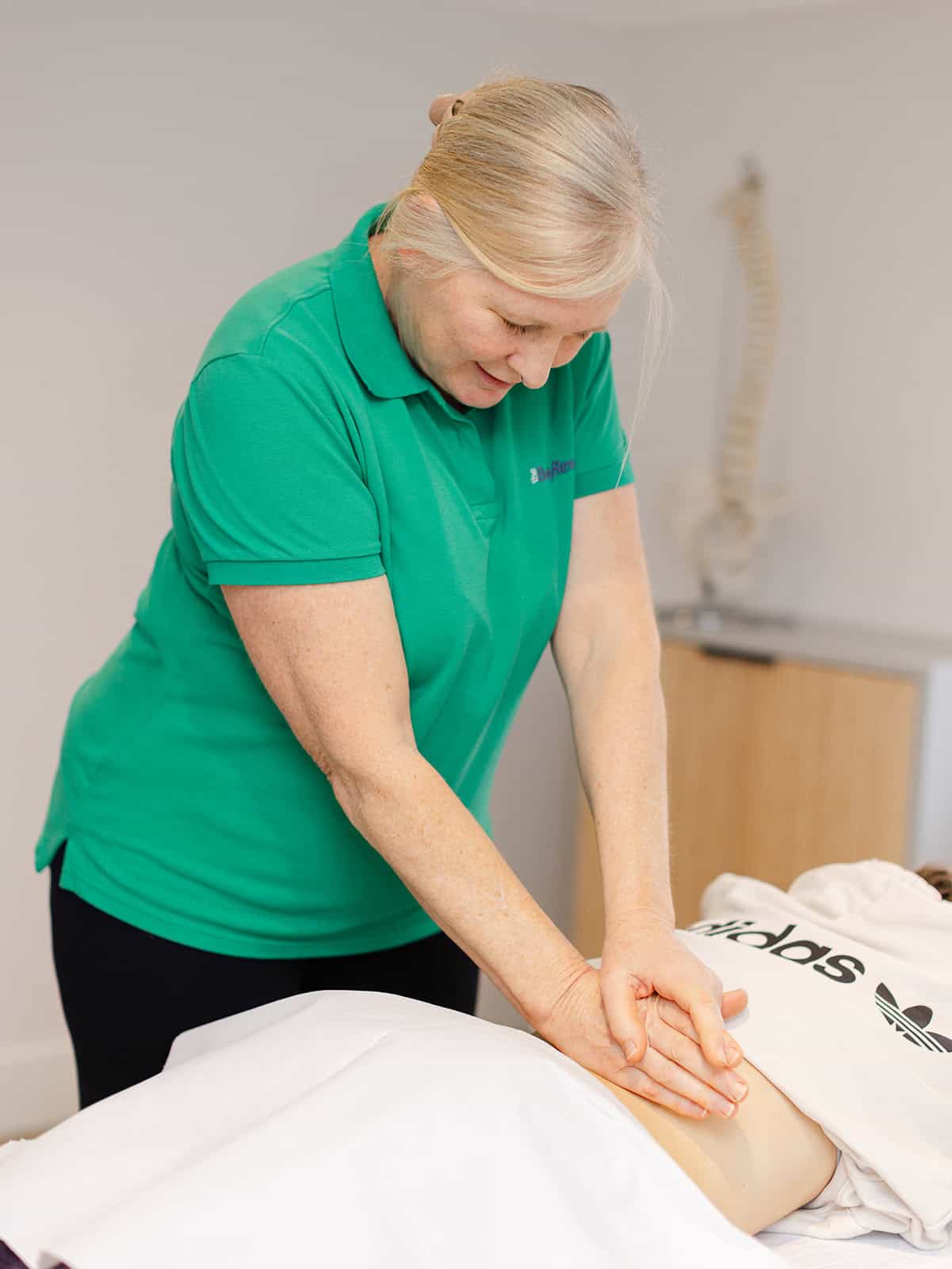 Rebecca Hardman diagnosing and treating a female client’s lower back for optimal recovery 